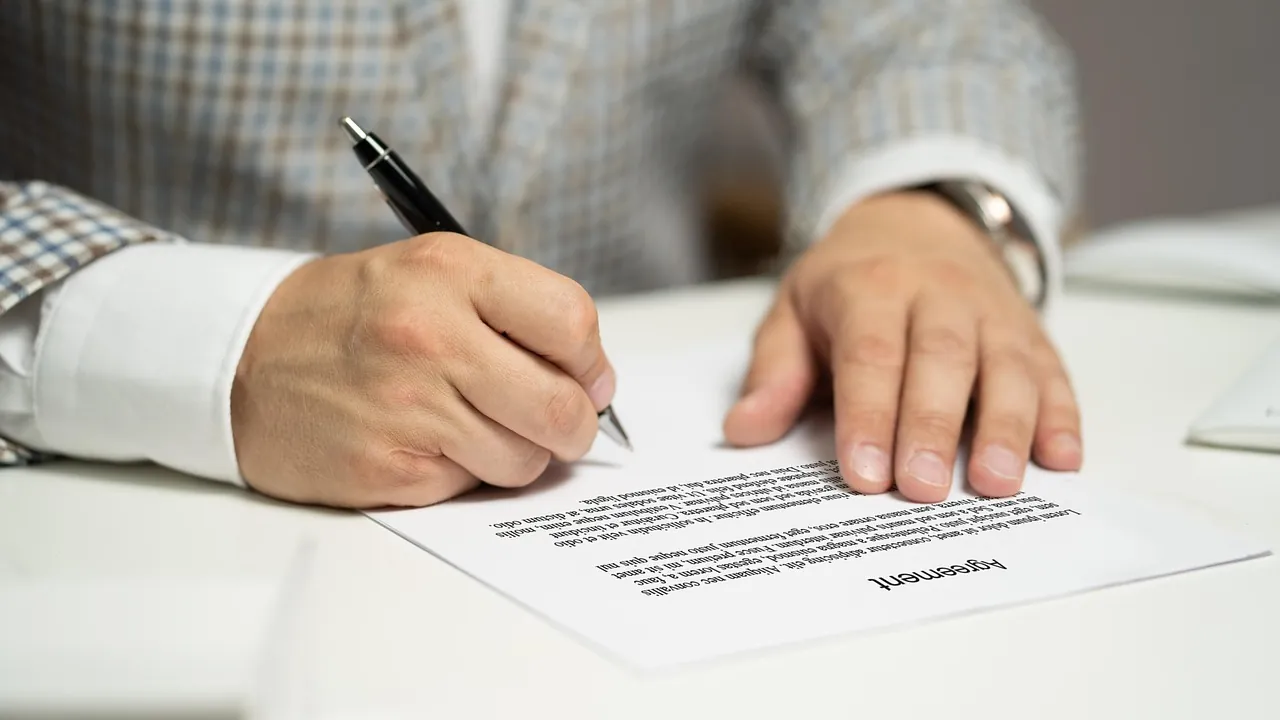 Deux paires de mains signant un document sur un bureau