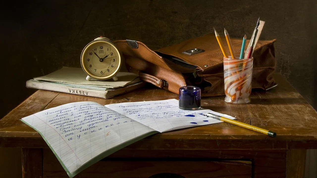 Un bureau ancien : cahier manuscrit ouvert, encrier et crayons